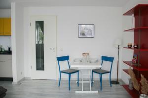 un comedor con una mesa blanca y sillas azules en CityOase Magdeburg im Hansapark, Studio 1, Tiefgarage, Netflix, Wi-Fi, Balkon, en Magdeburgo