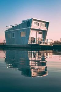 uma casa-barco na água com o seu reflexo na água em Tiny lake houses near the beach and centre em Zeewolde