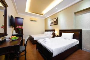 um quarto de hotel com duas camas e uma mesa e uma secretária em Nicecy Hotel - Bui Thi Xuan Street em Cidade de Ho Chi Minh