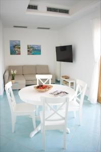 Fountain House Sorrento في سانتّانييلّو: غرفة معيشة بيضاء مع طاولة وكراسي بيضاء