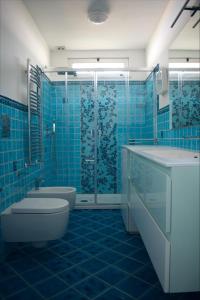 a blue tiled bathroom with a toilet and a shower at Fountain House Sorrento in Sant'Agnello