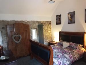 um quarto com uma cama num quarto com uma parede de pedra em orchard meadow holiday barn leek-buxton-Ashbourne em Buxton