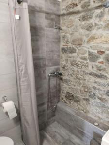 La salle de bains est pourvue d'une douche et d'un mur en pierre. dans l'établissement Light and sea 2, à Kavala