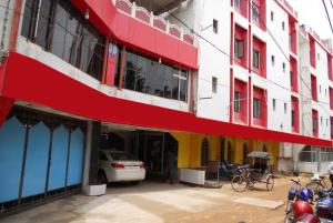 a red and white building with cars parked outside at Hotel Swagat Bhubaneswar in Bhubaneshwar