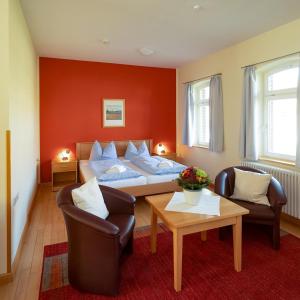 a bedroom with a bed and two chairs and a table at Biohotel Stiftsgut Wilhelmsglücksbrunn in Creuzburg