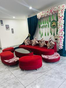 a room with red couches and a table and flowers at Raghav inn in Karnal