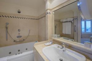 a bathroom with a sink and a tub and a mirror at Hotel Playa Victoria in Cádiz