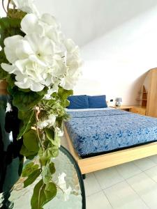 a bedroom with a bed and a vase with white flowers at Torrione Apartment in Giovinazzo