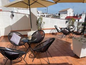 un patio avec des chaises et une table avec un parasol dans l'établissement Apartamentos San Fernando 76, à Cordoue