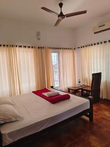 1 dormitorio con 1 cama grande y ventilador de techo en Timber Monk Beach Resort, en Pallipuram