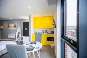 a kitchen with yellow cabinets and a table in a room at New studio balcony apartment in Sheffield in Sheffield