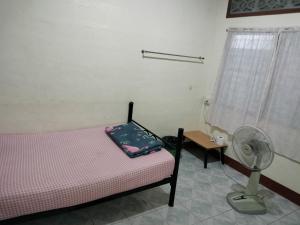 1 dormitorio con 1 cama, ventilador y mesa en Canaan Guesthouse, en Kanchanaburi