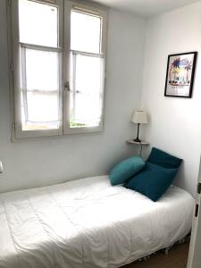 1 dormitorio con cama blanca y almohadas azules en Appartement Liseron en Saint-Martin-de-Ré
