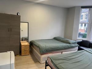 a bedroom with two beds and a mirror at Sterne Street 4 Person Room in London