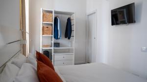 a white bedroom with a bed and a tv at Central Perk in Syracuse