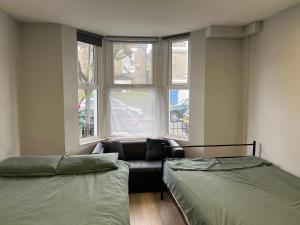 2 camas en una habitación con sofá y ventana en Sterne Street 4 Person Room en Londres