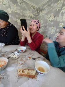 una mujer tomando una foto con su celular en una mesa en Kush, en Kochkorka