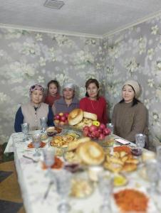un grupo de mujeres sentadas alrededor de una mesa con comida en Kush, en Kochkorka