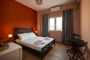 a bedroom with a bed with orange walls and a window at The Historical Center Studios in Athens