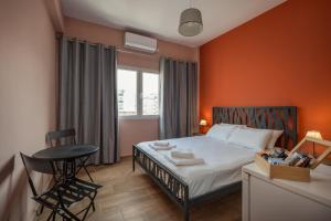 1 dormitorio con paredes de color naranja, 1 cama y 1 mesa en The Historical Center Studios, en Atenas