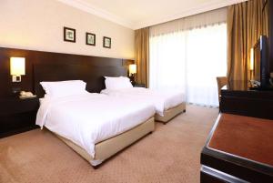a hotel room with two beds and a flat screen tv at Ramada Plaza by Wyndham Beirut Raouche in Beirut