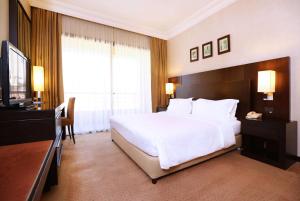 a bedroom with a large white bed and a television at Ramada Plaza by Wyndham Beirut Raouche in Beirut