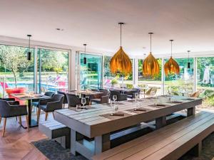 una sala da pranzo con tavoli, sedie e finestre di Novotel Lens Noyelles a Noyelles-Godault
