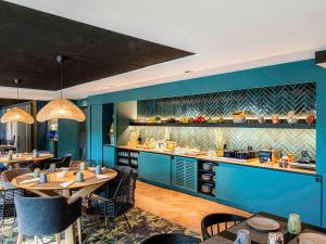 a restaurant with blue walls and tables and chairs at Novotel Lens Noyelles in Noyelles-Godault