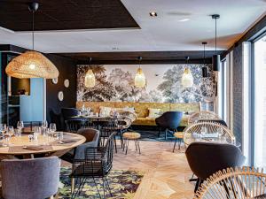 a restaurant with tables and chairs in a room at Novotel Lens Noyelles in Noyelles-Godault