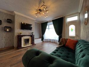 a living room with a green couch and a fireplace at Charming, spacious and cosy home in HULL in Hull