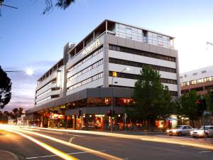 a building on a city street with a street at Novotel Canberra in Canberra