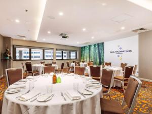 a conference room with tables and chairs and a stage at Novotel Canberra in Canberra