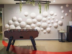 una parete con tavolo da ping pong in una stanza di ibis Styles Lyon Sud Vienne a Chasse-sur-Rhône