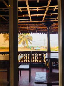 Blick auf eine Veranda mit Bänken und einer Palme in der Unterkunft Timber Monk Beach Resort in Pallipuram