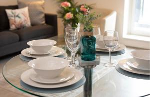 a glass table with plates and wine glasses on it at GuestReady - Beautiful apartment on Dublin Coast in Dublin