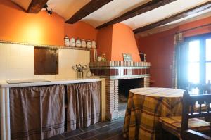 a kitchen with orange walls and a fireplace at Masía Finca La Sazadilla con Piscina in Albentosa