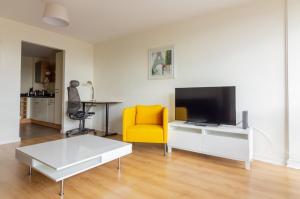 a living room with a tv and a yellow chair at GuestReady - Luminous Elegance in Barrow Street in Dublin