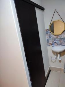 a black door in a bathroom with a sink at Kitnet na melhor localização JD Paulistano in Ribeirão Preto