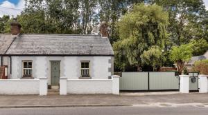 a white house with a gate and a fence at GuestReady - Opulence Malahide Seaside Cottage in Malahide