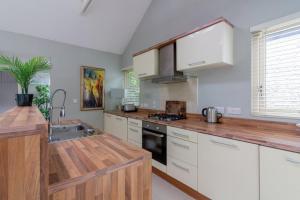 a kitchen with white cabinets and a wooden counter top at GuestReady - Opulence Malahide Seaside Cottage in Malahide