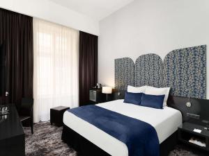 a hotel room with a large bed with a blue blanket at Hotel Nemzeti Budapest - MGallery in Budapest