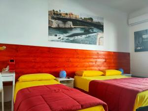 2 letti in una camera con rosso e giallo di B&B Castrogiovanni Affittacamere a Taranto