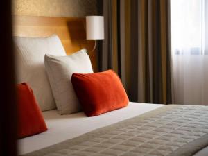 - une chambre avec un lit doté d'oreillers orange et blancs dans l'établissement Hotel Parc Beaumont & Spa Pau - MGallery, à Pau
