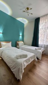 a bedroom with two beds and a blue wall at Отель ЭРА in Almaty