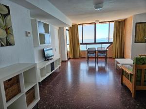 a living room with chairs and a tv and some windows at Apartamentos Don Vicente in Benidorm