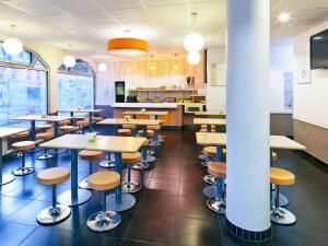 a restaurant with tables and stools in a cafeteria at ibis budget Blois Centre in Blois