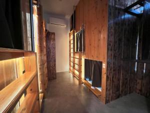 a room with wooden walls and a hallway with a shower at ゲストハウス JOOOY Hotel 奄美 in Amami