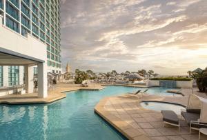 a hotel swimming pool with chairs and a building at Hilton Daytona Beach Resort in Daytona Beach