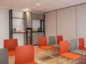 a waiting room with orange chairs and a refrigerator at ibis budget Nice Californie Lenval in Nice