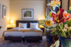 a bedroom with a bed and a vase of flowers at Landgoed Hotel & Restaurant Carelshaven in Delden
